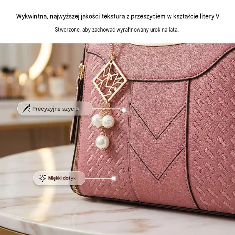 Damska torba na ramię z przeszyciami w kształcie litery V, złotymi okuciami, wieloma przegródkami i uchwytem u góry.